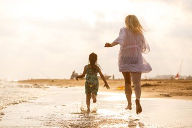 Genç anne ve kızı kumsalda eğleniyorlar. 