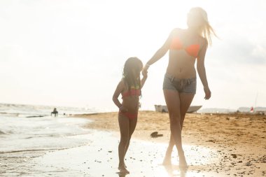 Genç anne ve kızı kumsalda eğleniyorlar. 