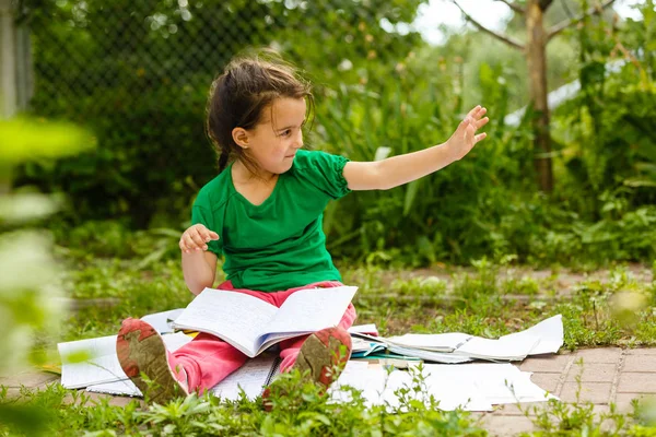 Kleines Mädchen Macht Hausaufgaben Auf Gras Grünen Frühlingspark — Stockfoto