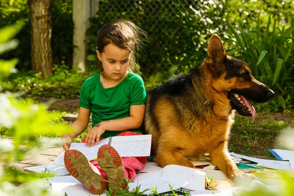 little girl and dog studying in green spring garden