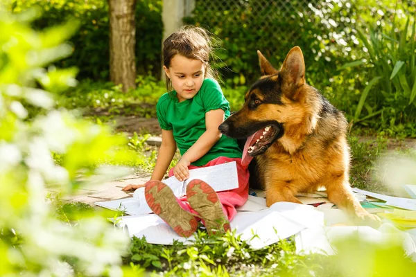 little girl and dog studying in green spring garden