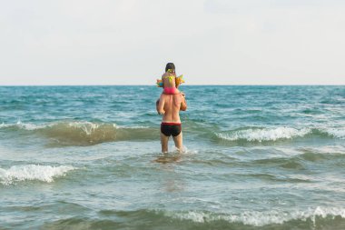 Genç baba ve kızı okyanus suyunda eğleniyor. 