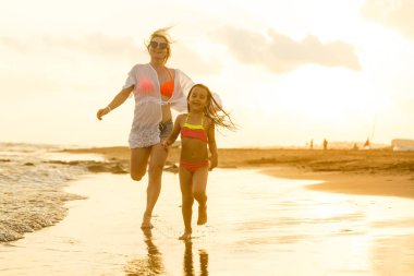 Genç anne ve kızı kumsalda eğleniyorlar. 