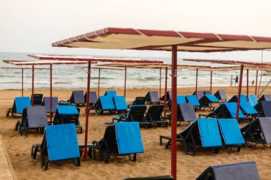 Mavi gökyüzü ve yaz arkaplanlı beyaz kumsalda güneşli yataklar. Yaz, Tatil, Seyahat ve Tatil konsepti.