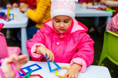 Küçük kız doğada bir inşaatçıyla oynuyor. sonbahar