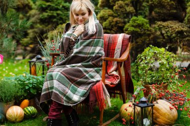 Parkta koltukta oturan yünlü battaniyeye sarılmış rahat sarışın kadın