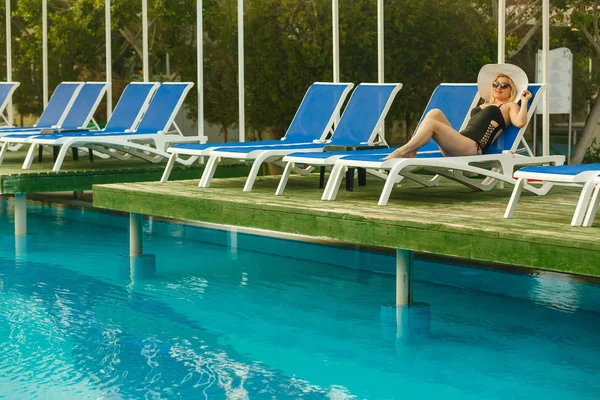 Siyah mayo lounge yanındaki yüzme havuzu güneşlenme içinde genç kadın