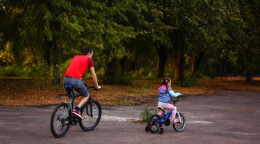 mutlu genç baba ve küçük kızı yeşil park bisiklet sürme