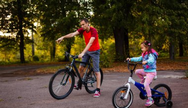 mutlu genç baba ve küçük kızı yeşil park bisiklet sürme