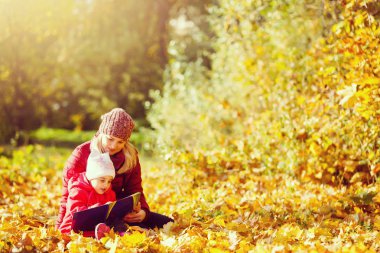 Anne ve kızı okuma kitabı birlikte Sonbahar Park Sonbahar yaprakları üzerinde