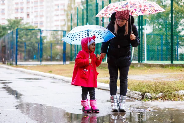 傘の下で公園で幼い娘を持つ若い女性 — ストック写真