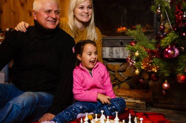 Büyükbaba ve anne öğretim torunu yazlık dekore edilmiş şömine ve Noel ağacı yakınındaki satranç oynamak için