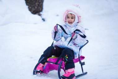 Mutlu kız oynarken ve karlı kış parkı çalışan