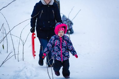 Küçük kız karlı kış parkında eğleniyor. 