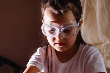 Küçük kız koruyucu gözlük ile İlköğretim Fen Bilgisi dersinde deney