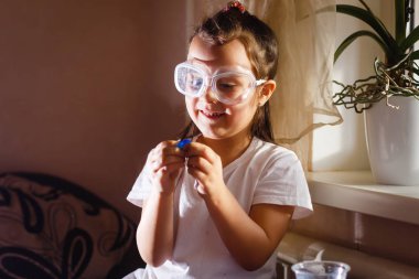 Küçük kız koruyucu gözlük ile İlköğretim Fen Bilgisi dersinde deney