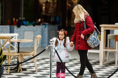 Anne ve kızı şehirde yürüyor.