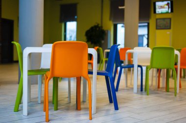 Renkli sandalyeleri ve masaları olan bir kafe.