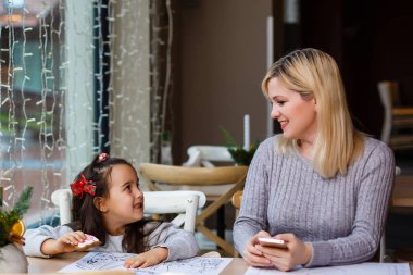 Noel dekore kafede küçük kızı ile genç anne