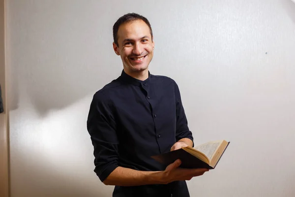 Man in black shirt holding holy bible on white background