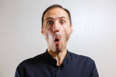 Gri arka planda poz veren yüzünde grimace olan genç beyaz adamın portresi 