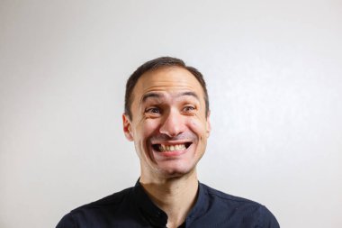 Gri arka planda poz veren yüzünde grimace olan genç beyaz adamın portresi 