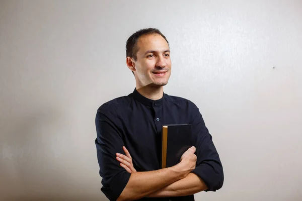 Man in black shirt holding holy bible on white background