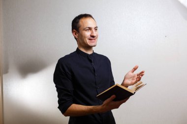 Beyaz arka planda kutsal İncil tutan siyah gömlekli adam 