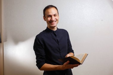 Beyaz arka planda kutsal İncil tutan siyah gömlekli adam 