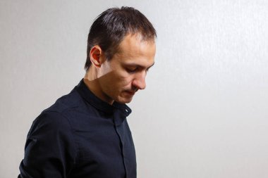 Gri arka planda poz veren yüzünde grimace olan genç beyaz adamın portresi 