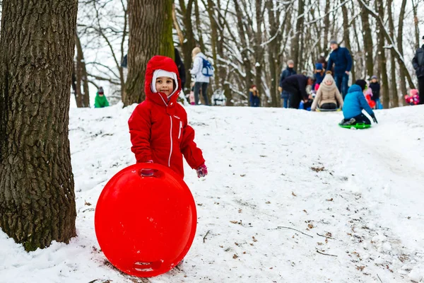 Usmívající Dívka Červeném Lyžařském Obleku Sesunuje Sněhem Pokrytého Kopce Sáňky — Stock fotografie