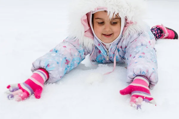 穿着蓬松外套在雪地操场上玩耍的小女孩 — 图库照片
