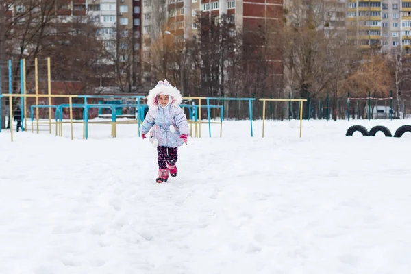 穿着蓬松外套在雪地操场上玩耍的小女孩 — 图库照片