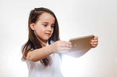 Beyaz arka planda akıllı telefon tutan esmer küçük kız