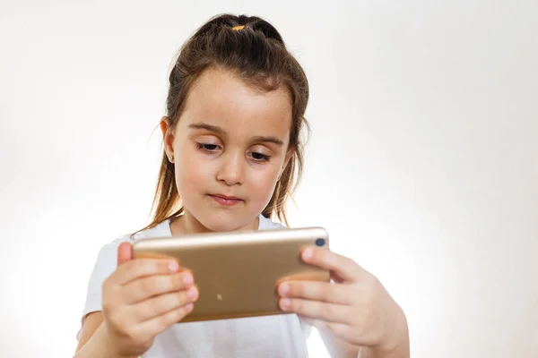 Brünettes Kleines Mädchen Mit Smartphone Auf Weißem Hintergrund — Stockfoto
