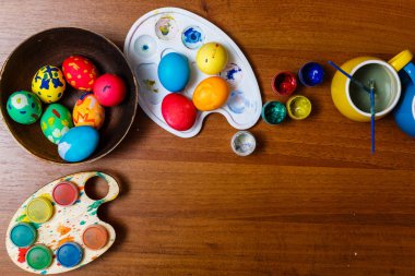 Ahşap masa üzerinde boyalı paskalya yumurtaları ve guaj