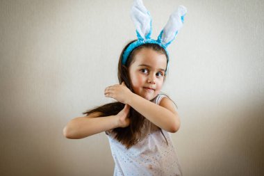 Açık arka planda mavi tavşan kulakları ile küçük kız