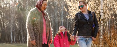 Üç kuşak kızı, anne ve büyükanne güneşli parkta yürüyüş