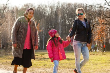 Üç kuşak kızı, anne ve büyükanne güneşli parkta yürüyüş