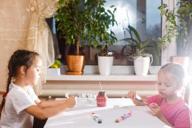 Evde renkli resim çizen iki küçük kız kardeş