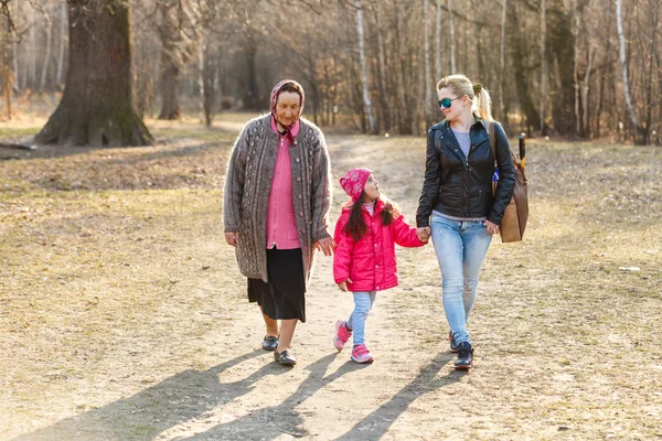 Three generations daughter, mother and grandmother walking in sunny park