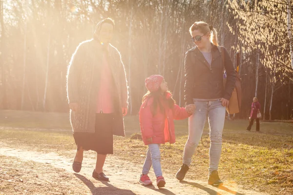 Three generations daughter, mother and grandmother walking in sunny park