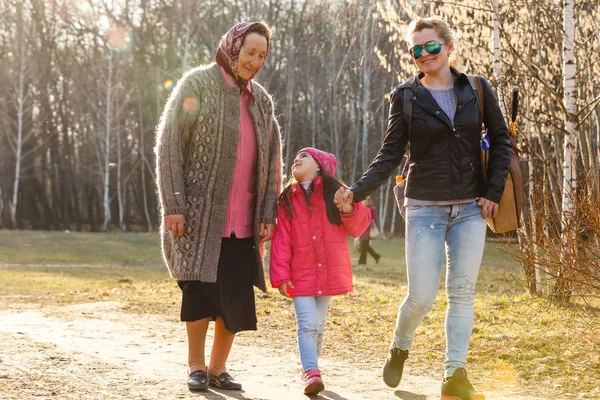 Three generations daughter, mother and grandmother walking in sunny park