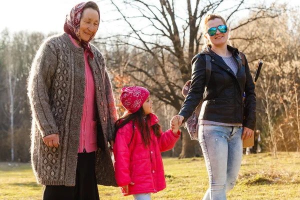 Three generations daughter, mother and grandmother walking in sunny park