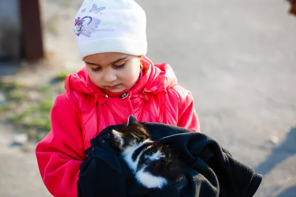Mała Dziewczynka Trzyma Małego Kociaka Owiniętego Czarną Tkaninę — Zdjęcie stockowe