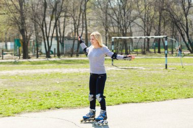 Spor kıyafetli genç bir kadın parkta ip atlamakla egzersiz yapıyor.