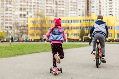 Küçük kız şehirde scooter kullanıyor.