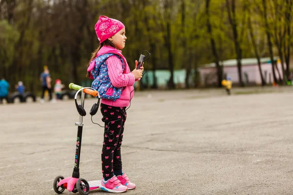 Menina Montando Scooter Com Smartphone Playground — Fotografia de Stock