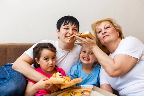 子供を持つ母と祖母は 自宅で大きなピザを食べる — ストック写真