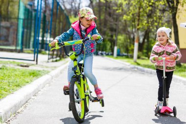 Parkta scooter süren küçük bir kız.